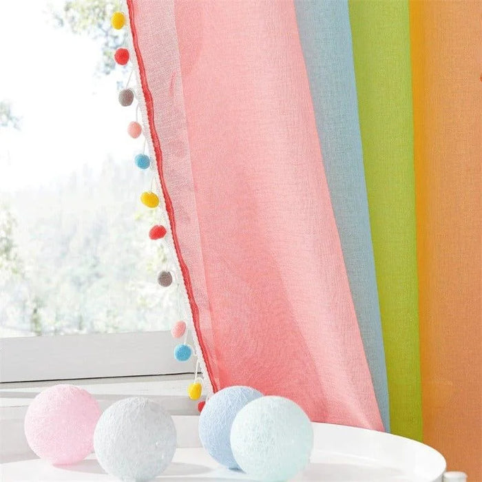 Rideau coloré avec pompons décoratifs sur le bord, idéal pour ajouter une touche de fraîcheur et de gaieté à toute pièce. Accompagné de petites décorations sphériques, ce rideau est parfait pour créer une ambiance lumineuse et accueillante dans un salon ou une chambre d'enfant.