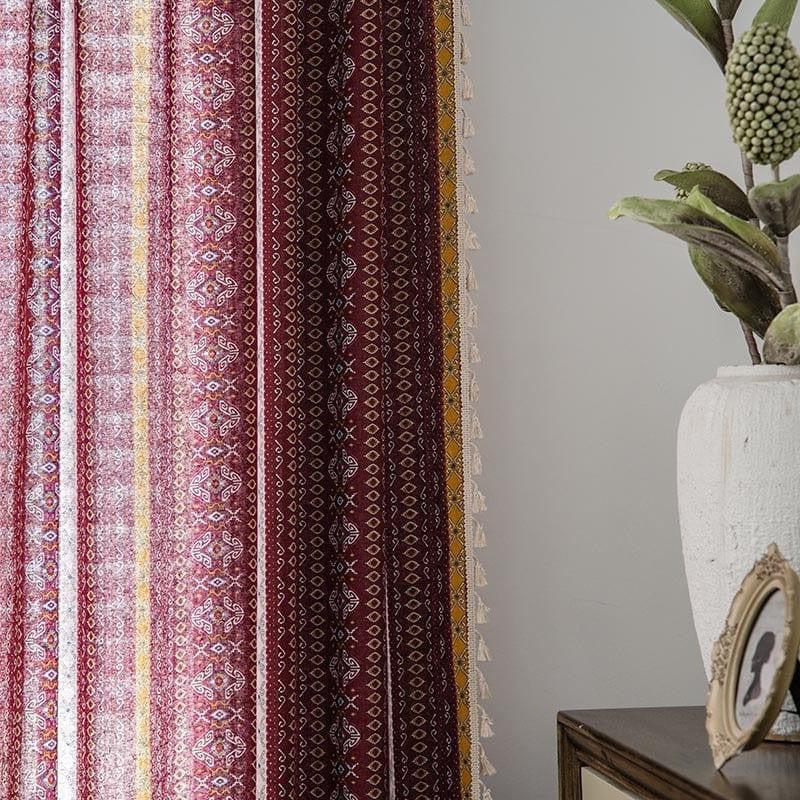 Rideaux décoratifs à motifs ethniques rouges et jaunes pour un intérieur chaleureux et élégant, accompagnés d'une plante verte en pot et d'un cadre sur une commode.
