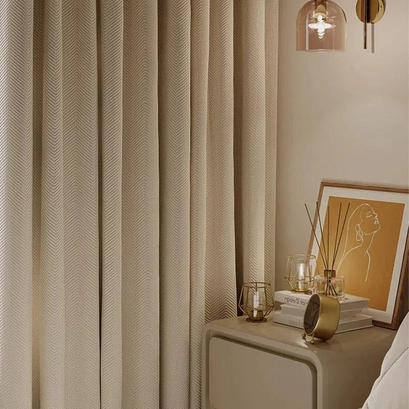 Rideau beige pour chambre élégante, suspendu près d'une table de chevet avec livres, décorations modernes et lampe design, créant une atmosphère chaleureuse et sophistiquée. Idéal pour un intérieur raffiné et contemporain.
