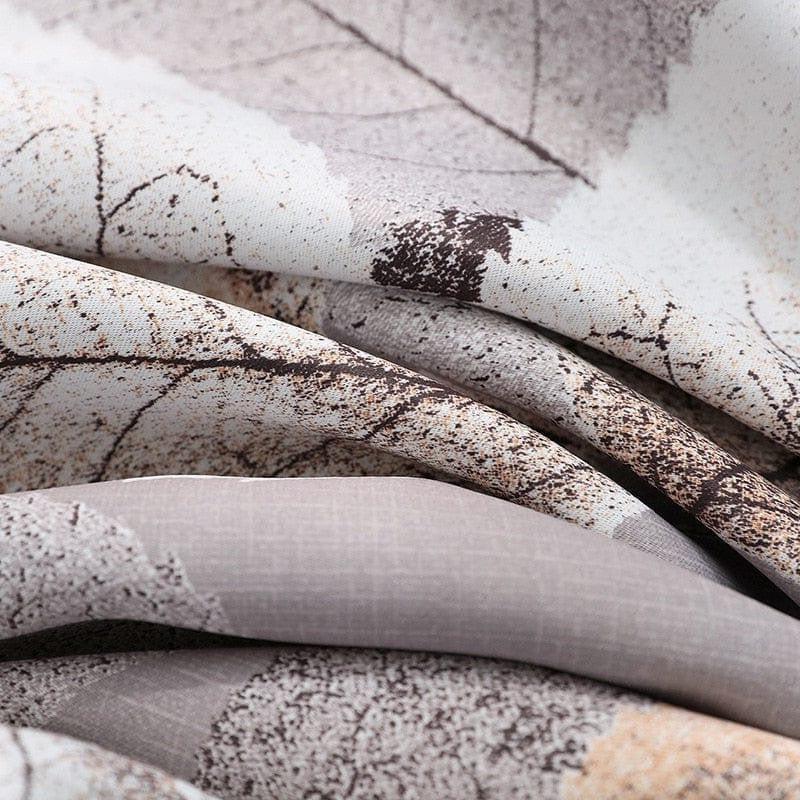 Gros plan sur un tissu imprimé avec des motifs de feuilles, mélange subtil de teintes naturelles marron et crème. Design élégant et moderne, idéal pour créer une ambiance chaleureuse et sophistiquée dans une décoration intérieure. Parfait pour le linge de maison ou les projets de décoration.
