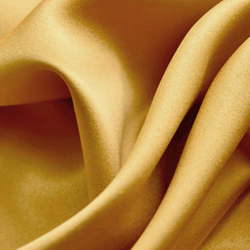 Texture fluide de tissu doré brillant, mettant en valeur un effet lumineux et élégant pour ajouter une touche de luxe à tout intérieur ou vêtement. Idéal pour la décoration ou la mode, ce textile ondulé offre une sensation visuelle de douceur et de raffinement.