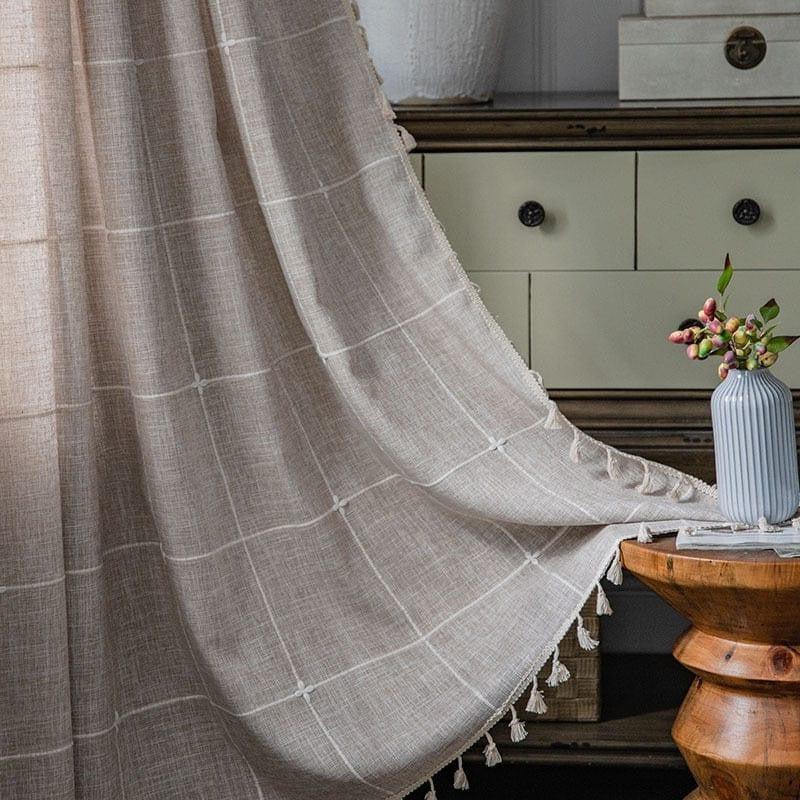 Voilage élégant beige avec motif à carreaux pour une décoration intérieure raffinée. Ce rideau apporte une touche chaleureuse et moderne à votre salon. Il s'intègre parfaitement dans un intérieur chic avec un meuble en bois, mettant en valeur le design d'une table ronde et des accessoires décoratifs comme un vase blanc aux fleurs délicates. Transformez votre espace avec ce rideau au style intemporel, idéal pour filtrer la lumière tout en créant une ambiance conviviale.