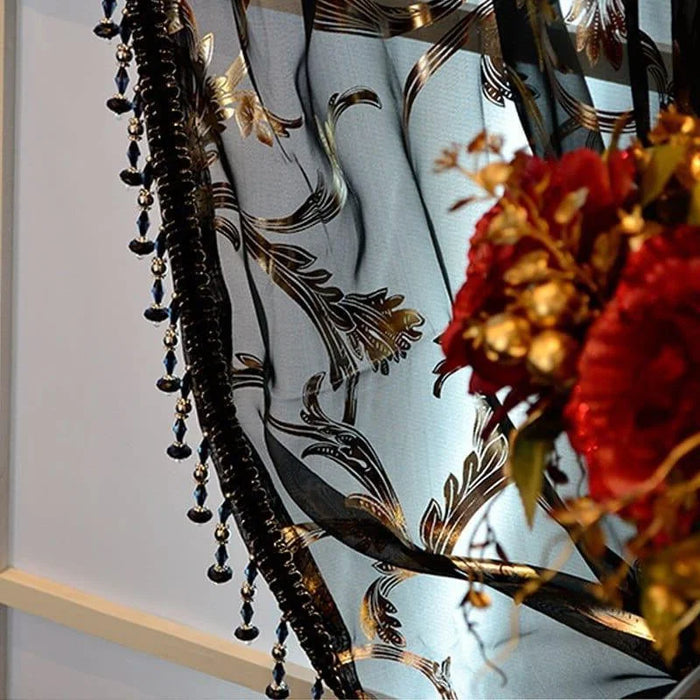 Rideau décoratif avec motifs floraux noirs et dorés, agrémenté de perles suspendues, idéal pour ajouter une touche d'élégance et de sophistication à votre intérieur. Les motifs raffinés fusionnent harmonieusement avec un joli bouquet de fleurs rouges, créant une ambiance chaleureuse et luxueuse dans la pièce. Parfait pour embellir salons et chambres avec style et charme.