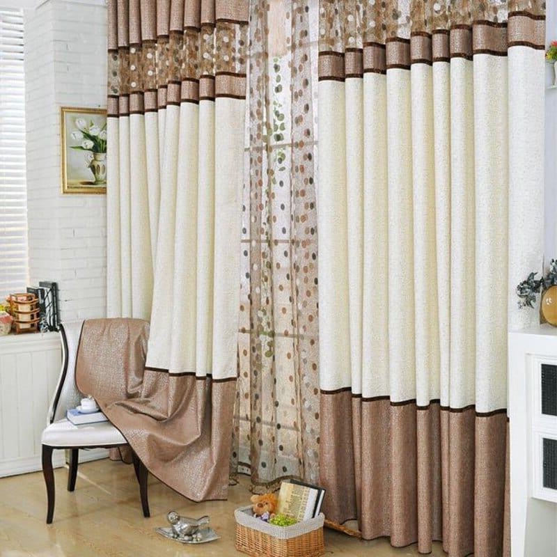 Rideaux élégants dans un salon moderne, combinant des tons crème et marron pour une ambiance chaleureuse. Décoration avec motifs délicats et accessoires de lecture, accentuant un style chic et confortable. Solution idéale pour optimiser la lumière naturelle tout en ajoutant une touche sophistiquée à la pièce.
