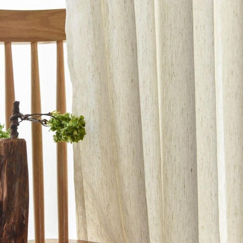 Chaises en bois élégantes avec rideaux légers pour une ambiance naturelle et apaisante dans le salon. Décoration sobre intégrant un vase original, idéal pour un intérieur moderne et chaleureux.