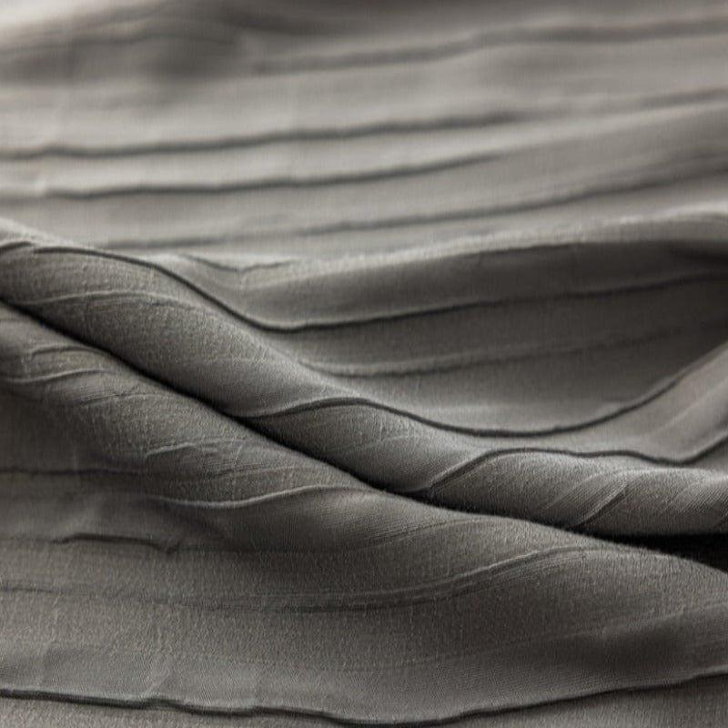 Texture de tissu gris aux plis élégants, idéale pour la confection de vêtements raffinés ou de décorations d'intérieur modernes. Ce design subtil ajoute une touche de sophistication à tout projet créatif.