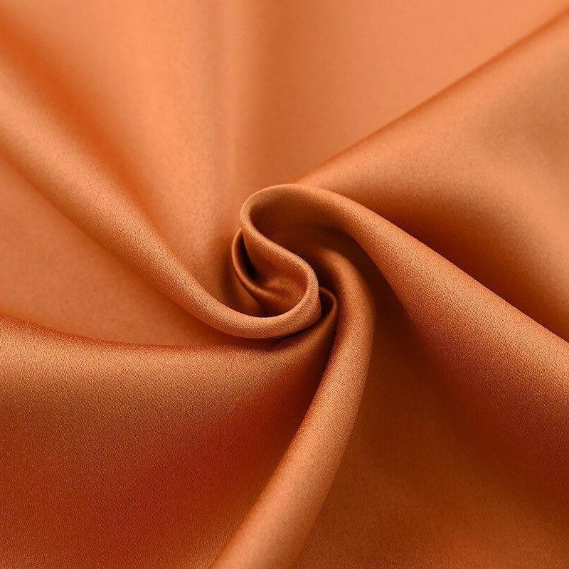 Texture enroulée de tissu couleur orange safran, présentant un aspect lisse et élégant, idéale pour la décoration intérieure ou la confection de vêtements sur mesure.