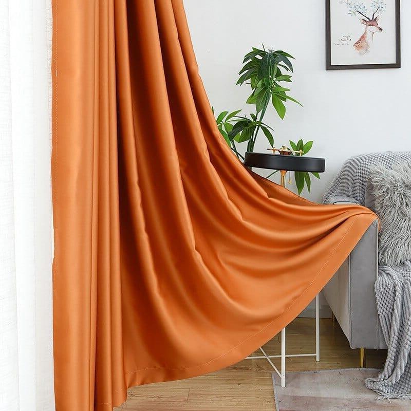 Rideau élégant de couleur orange ajoutant une touche moderne et chaleureuse à votre salon. Idéal pour créer une ambiance raffinée, il s'accorde parfaitement avec une décoration intérieure contemporaine. Le rideau est présenté dans un salon lumineux avec des éléments de décoration harmonieux, notamment une plante verte et un cadre mural artistique. Parfait pour habiller vos fenêtres tout en offrant une performance décorative optimale.