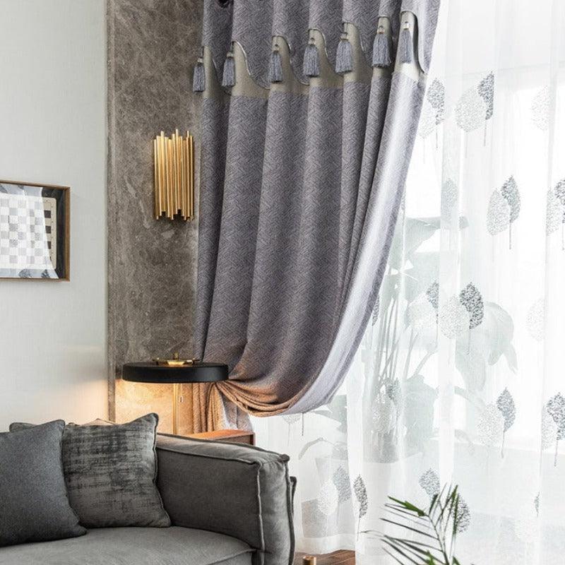 Rideaux élégants pour salon moderne, combinant des tons gris avec des motifs subtils, ornés de pompons raffinés. Parfaits pour ajouter une touche de sophistication à la déco intérieure, ces rideaux se marient harmonieusement avec des canapés contemporains et des luminaires dorés. Transformez votre espace de vie avec style et élégance.