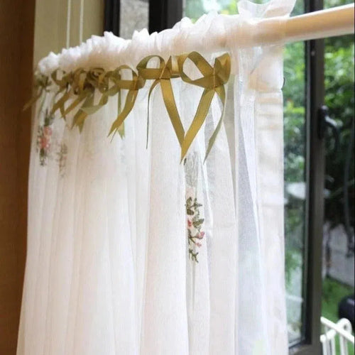 Rideau déco élégant avec rubans ornés de motifs floraux, idéal pour une ambiance romantique dans une chambre ou un salon. Ce rideau blanc laisse passer la lumière tout en ajoutant une touche de charme classique à votre intérieur. Parfait pour les fenêtres modernes, il crée une atmosphère douce et accueillante.