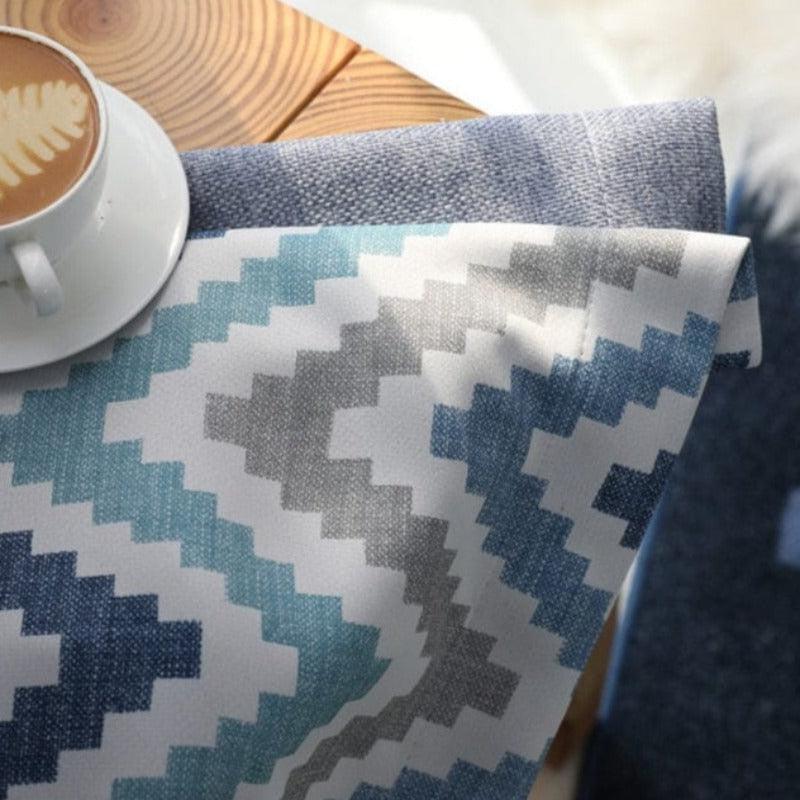 Tissu à motifs zigzag bleu et gris sur fond blanc, idéal pour la décoration intérieure. Parfait pour moderniser un espace avec une touche de couleur et de style géométrique. Accessoire polyvalent pour la maison.