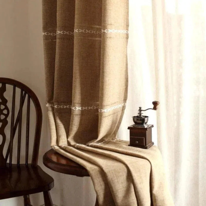 Rideau élégant de couleur beige avec motifs brodés subtils, idéal pour ajouter une touche chaleureuse et accueillante à votre intérieur. Accessoire de décoration parfait pour le salon, la chambre ou la salle à manger, offrant une ambiance cosy. Accessoire complémentaire à côté d'une chaise en bois classique et d'un moulin à café vintage.