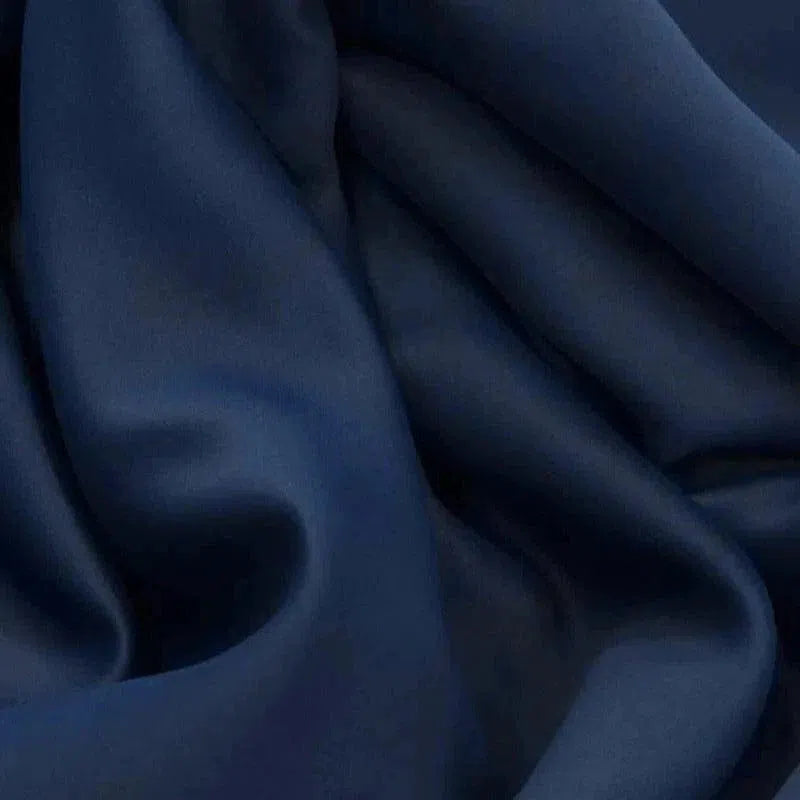 Gros plan sur un tissu bleu marine élégant avec des plis doux, idéal pour un drapé élégant dans la confection vestimentaire ou la décoration d'intérieur. Ce tissu est parfait pour créer une atmosphère sophistiquée et moderne.