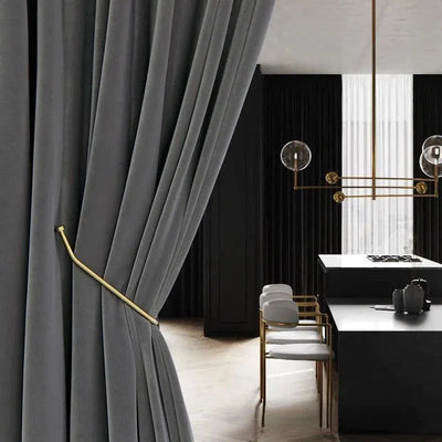 Rideau élégant gris foncé dans un intérieur moderne, avec un embrasse en métal doré, ajoutant une touche de sophistication au salon, combiné avec un mobilier chic et contemporain sous un éclairage design.