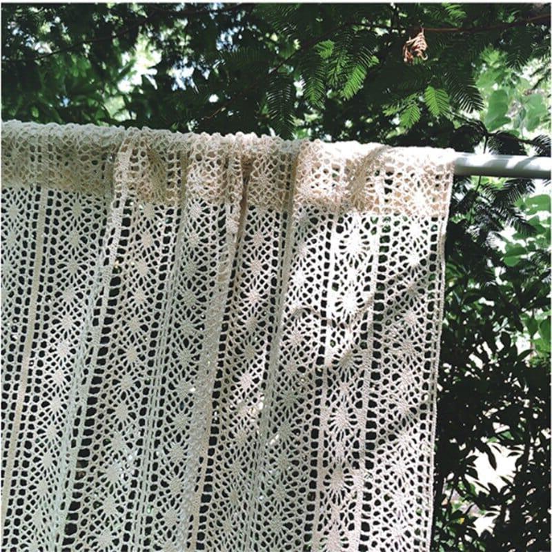 Rideau en dentelle crocheté à la main suspendu dans un jardin ensoleillé, idéale pour ajouter une touche bohème et élégante à votre décoration intérieure. Parfait pour une ambiance naturelle et lumineuse.