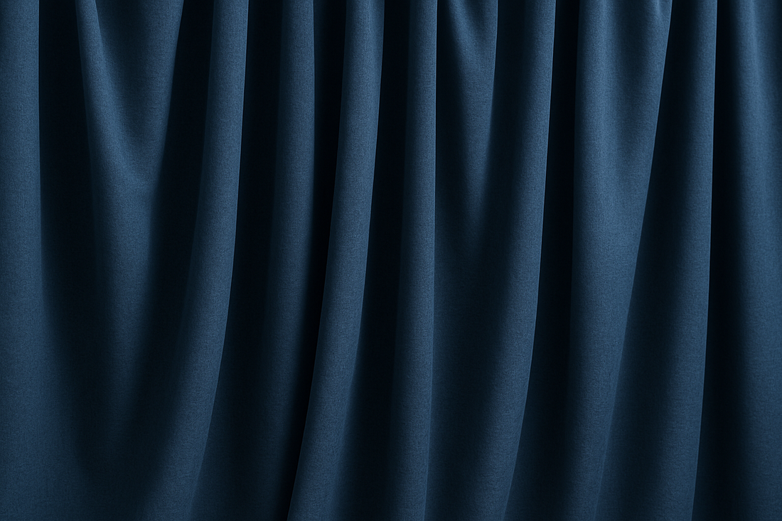 Rideaux occultants bleu foncé légèrement froissés, suspendus en plis souples, illustrant leur texture épaisse et leur tombé naturel dans un intérieur sobre.