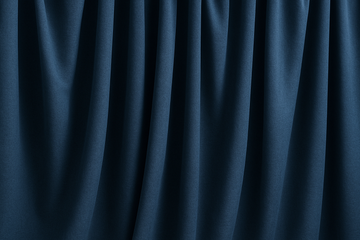 Rideaux occultants bleu foncé légèrement froissés, suspendus en plis souples, illustrant leur texture épaisse et leur tombé naturel dans un intérieur sobre.
