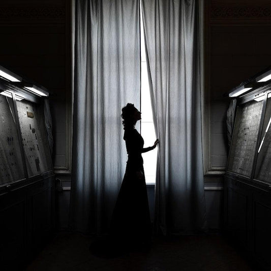 Une légère étoffe voile la fenêtre de la chambre, laissant filtrer la lumière du jour pour une ambiance douce et intime.