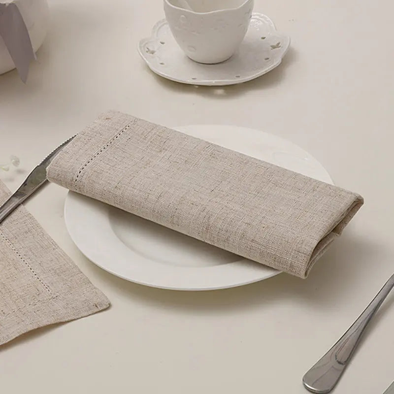 Une serviette de table grise et texturée repose sur une assiette blanche, accompagnée d'une tasse et d'un couteau.
