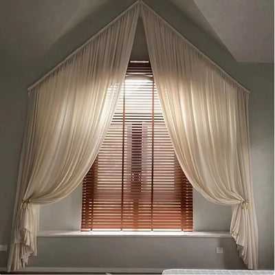 Rideau trapèze irrégulier en tulle transparent suspendu à une fenêtre française