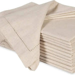 Pile de serviettes de table en lin beige, avec des points de couture élégants.