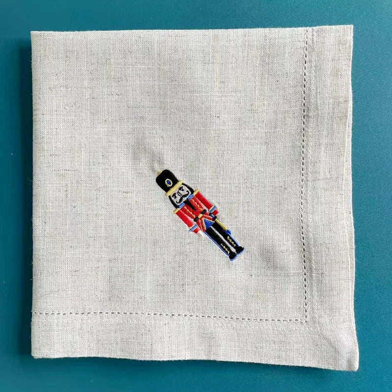 Sur un mouchoir en lin beige, un petit soldat en costume militaire est brodé.