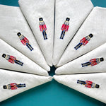 Des serviettes en lin brodées de petits soldats en uniforme britannique.