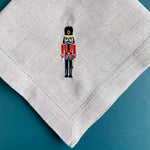 Un soldat de noël en uniforme orné d'une figure emblématique est brodé sur un mouchoir blanc.