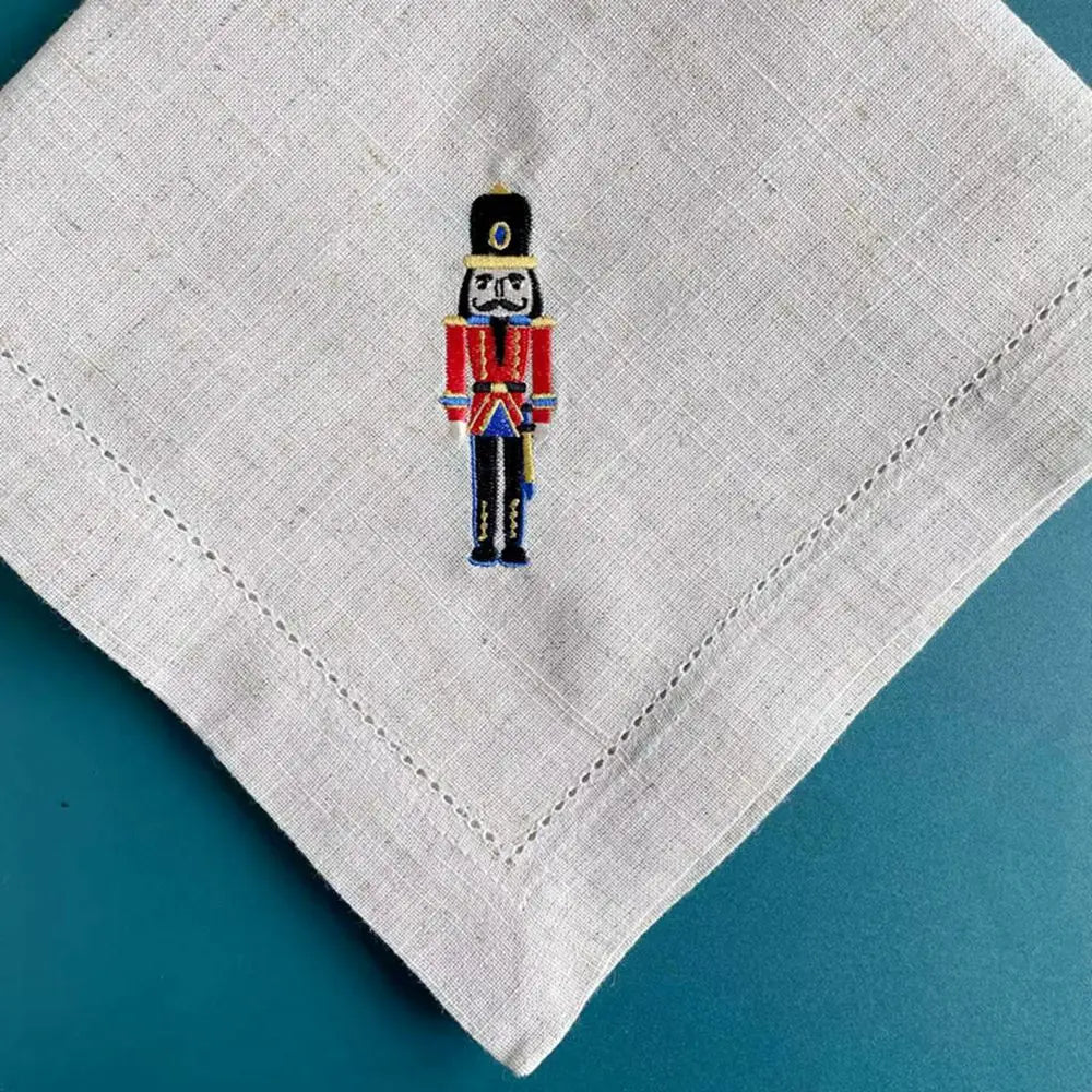 Un soldat de noël en uniforme orné d'une figure emblématique est brodé sur un mouchoir blanc.