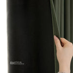 Main dévoilant la doublure sombre du rideau thermique vert sapin conçu pour bloquer la lumière