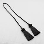  Embrasse noire pour rideau avec deux pompons fins, style minimaliste et raffiné pour tout type d’intérieur.