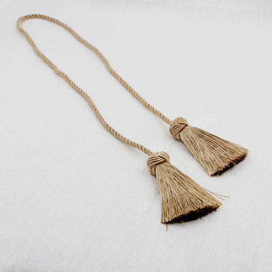 Embrasse rideau torsadée de couleur beige clair avec deux pompons, idéale pour une déco chaleureuse et naturelle.