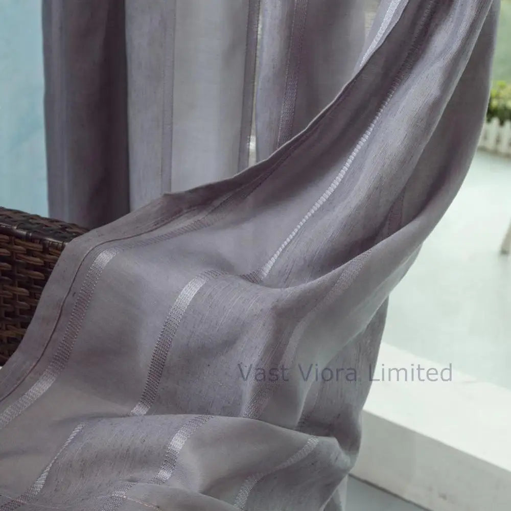 Voilage gris foncé flottant dans un courant d’air, laissant passer la lumière naturelle tout en préservant l’intimité.