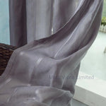 Voilage gris foncé flottant dans un courant d’air, laissant passer la lumière naturelle tout en préservant l’intimité.