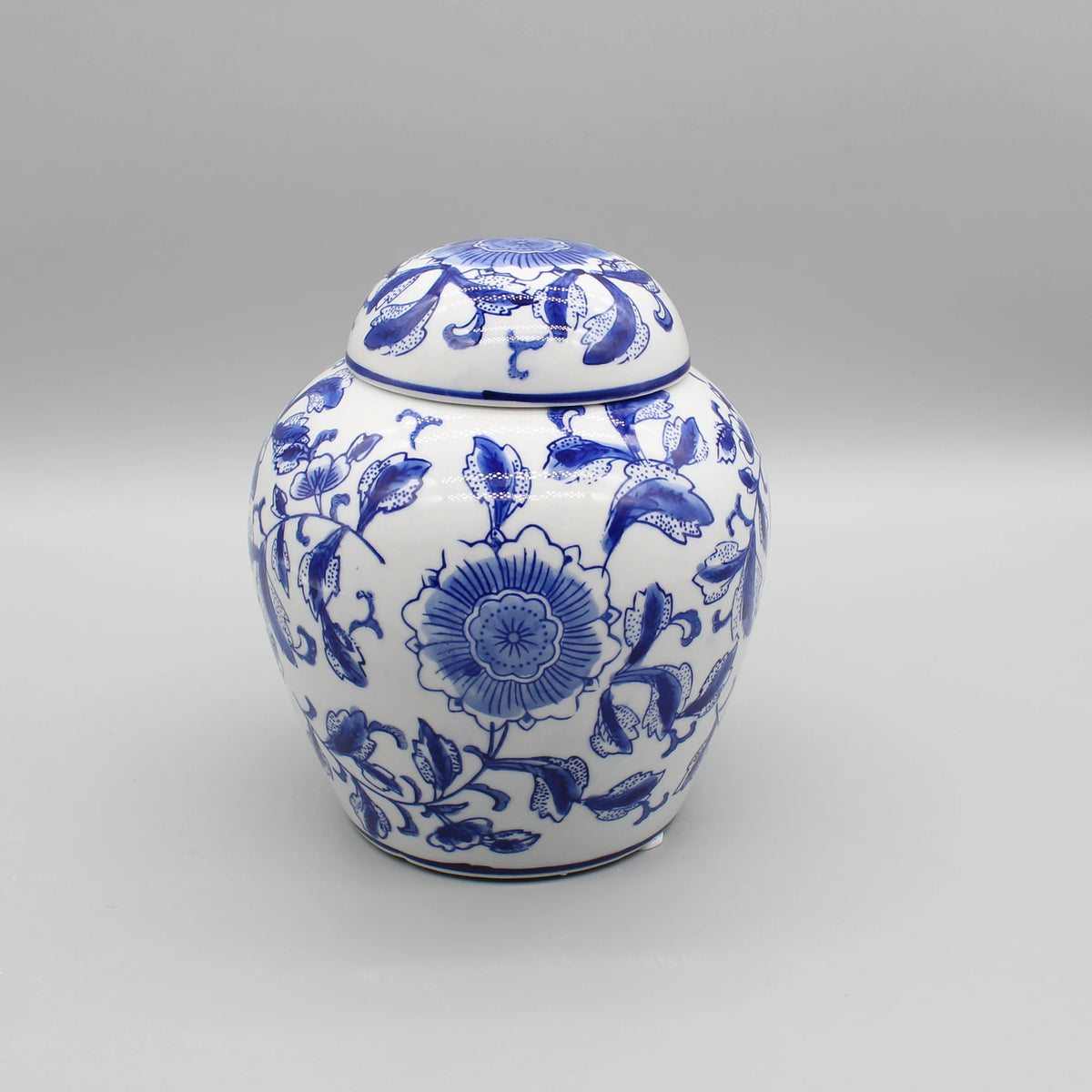 Un pot en céramique décoré de motifs floraux bleus et blancs, avec un couvercle assorti, offrant un bel élément de décoration pour un intérieur.