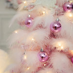 Détail des plumes roses et des ornements bleus du mini arbre de Noël