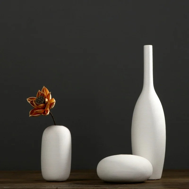 Un vase blanc élégant et un objet de décoration en forme de fleur posés sur une surface en bois.