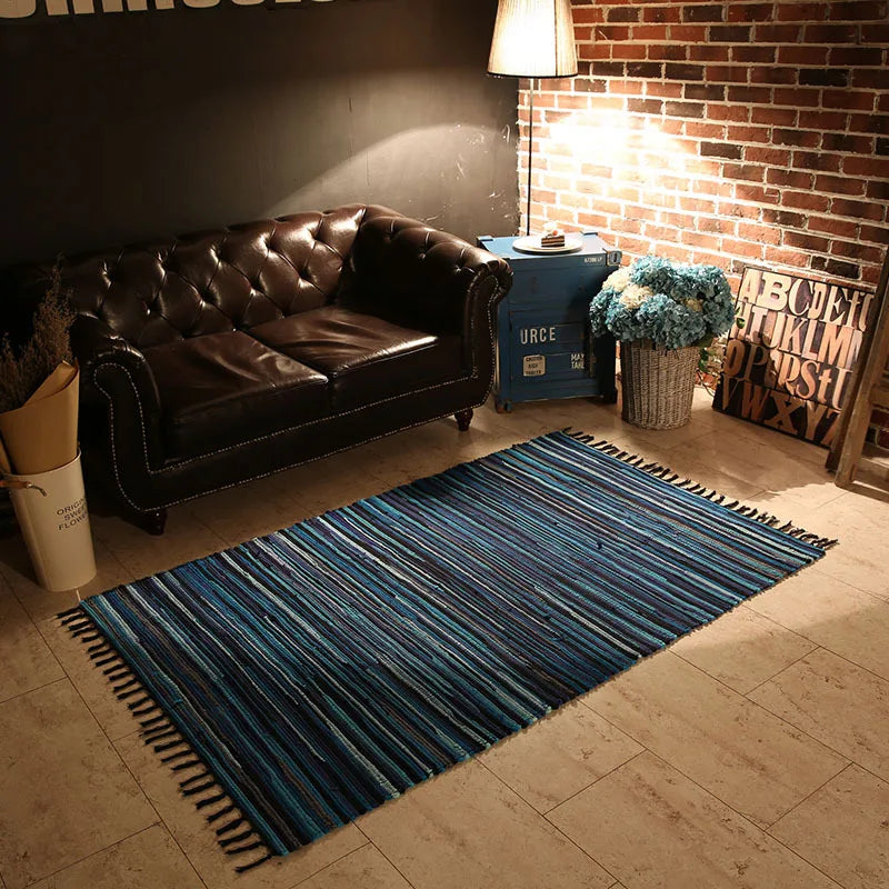 Un intérieur cosy avec un canapé en cuir marron, une lampe et des éléments de décoration comme une plante et un tapis rayé dans des tons bleus.