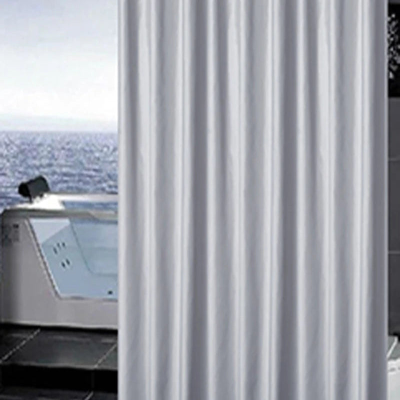 Gros plan sur un rideau de douche uni de couleur gris argenté, suspendu à côté d’une baignoire avec vue sur la mer en arrière-plan.