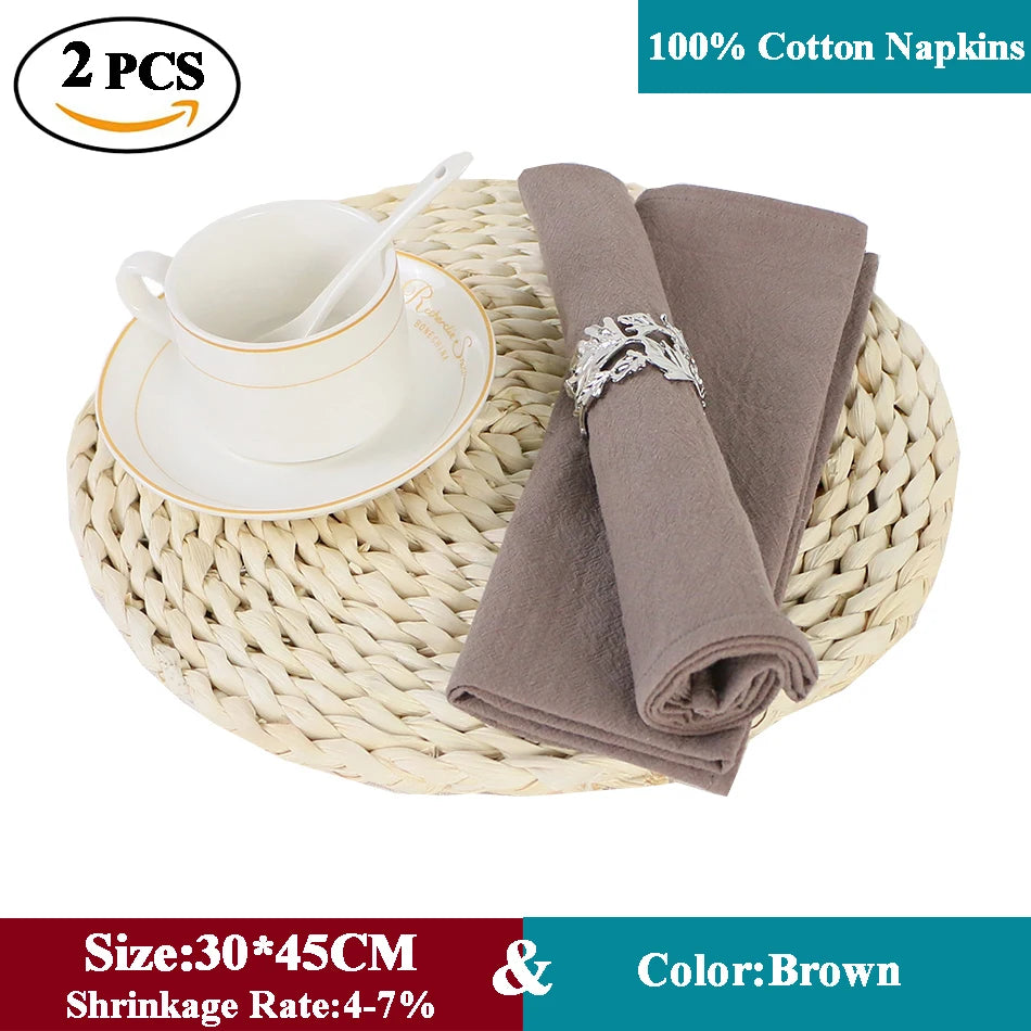 Des serviettes en coton marron de haute qualité, placées sur un support en osier, accompagnées d'une tasse blanche et d'un anneau décoratif.