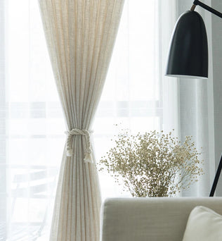 Voilage effet lin naturel noué élégamment au centre, laissant passer la lumière dans un salon lumineux à la décoration épurée.