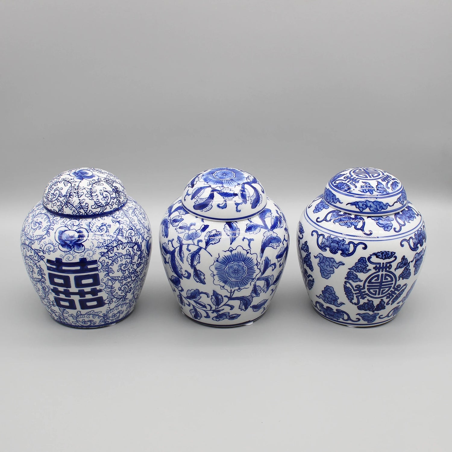 Trois bocaux en porcelaine bleu et blanc ornés de motifs floraux et de symboles traditionnels chinois.