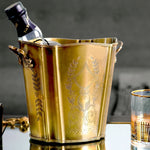 Le seau à glace doré, finement décoré de motifs floraux et de feuilles, présente une allure élégante et raffinée, parfaite pour rafraîchir une bouteille de vin ou de champagne lors d'un événement spécial.