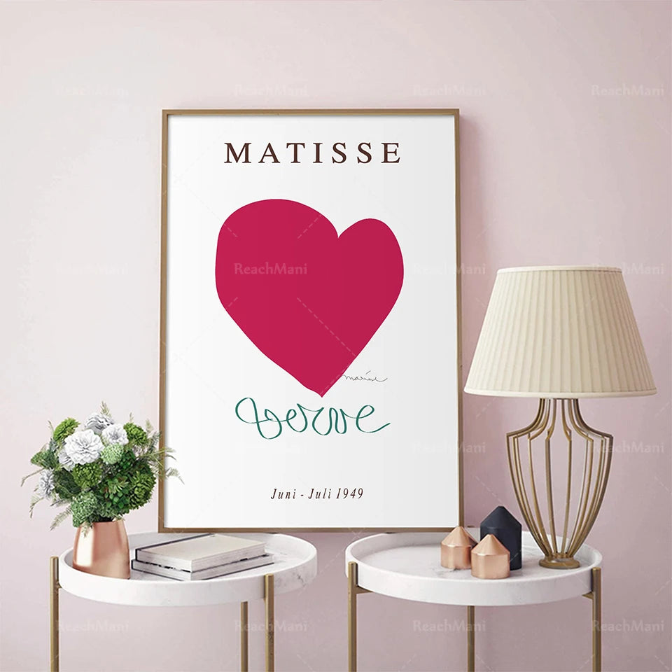 Affiche murale encadrée avec le texte "MATISSE" et un grand cœur rose, sur fond blanc, entourée de décorations de style élégant.