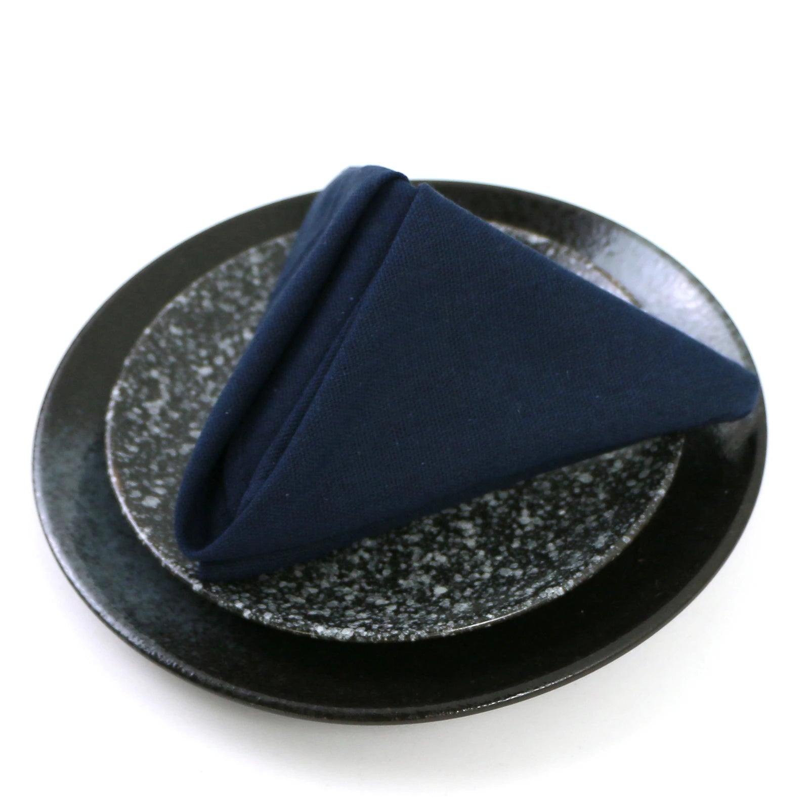 Un morceau de tissu bleu foncé plié sur un support noir texturé.