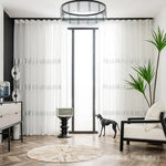 Salon lumineux décoré avec de grands rideaux blancs en tulle brodé.