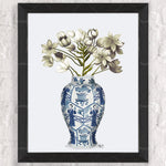 Vase bleu et blanc orné de motifs floraux exotiques contenant un bouquet de délicates fleurs blanches et vertes.
