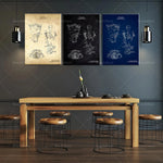 Cette image montre un intérieur moderne avec un grand espace de vie, une table en bois massif et des tabourets sur mesure. Au mur, on peut voir trois affiches illustrant un design breveté en noir et blanc ainsi qu'en bleu.