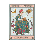 L'image montre une femme vêtue d'une robe fleurie tenant une pelote de laine, entourée de symboles astrologiques et de motifs floraux, représentant la carte de tarot "le Tricoteur".