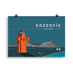 Le phare de Krossvik, sur une île d'Islande, domine le paysage de montagnes brumeuses et de maisons blanches sur fond de ciel bleu sombre.